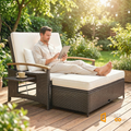 Sfeerco Rivea outdoor rattan daybed with couple relaxing on wooden deck surrounded by garden greenery